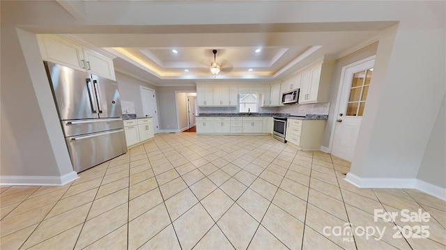 kitchen featuring appliances with stainless steel finishes, white cabinets, decorative backsplash, light tile patterned floors, and a raised ceiling