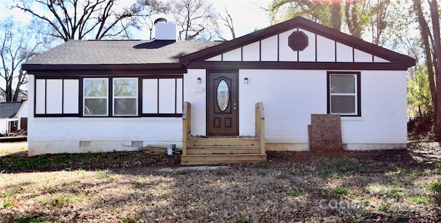 view of front of property with entry steps, a chimney, crawl space, board and batten siding, and brick siding