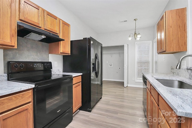 kitchen with visible vents, a sink, light wood-type flooring, under cabinet range hood, and black appliances