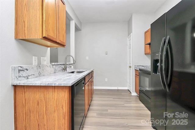 kitchen featuring black appliances, light wood-style floors, brown cabinetry, and a sink