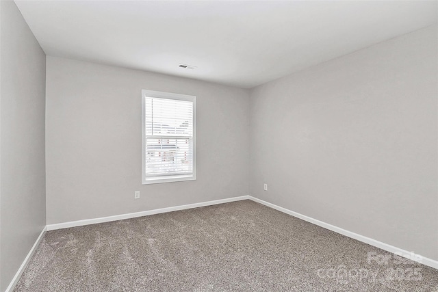 spare room featuring carpet, visible vents, and baseboards