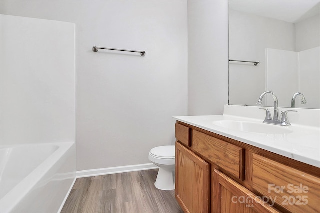 full bathroom with toilet, vanity, wood finished floors, baseboards, and a bath