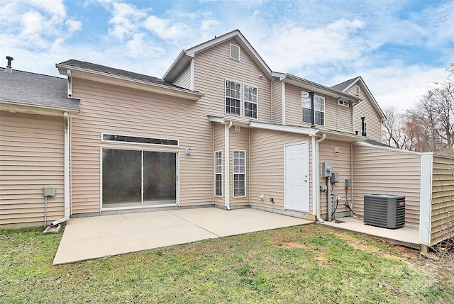 rear view of house with central AC, a lawn, and a patio