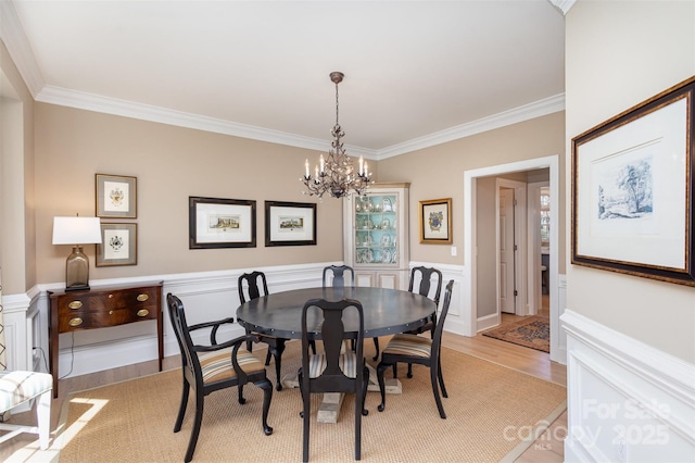 dining area featuring an inviting chandelier, crown molding, and light wood-type flooring