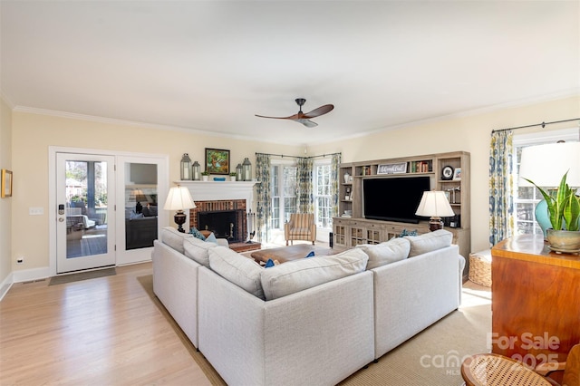 living room with ornamental molding, a brick fireplace, light wood-type flooring, and ceiling fan