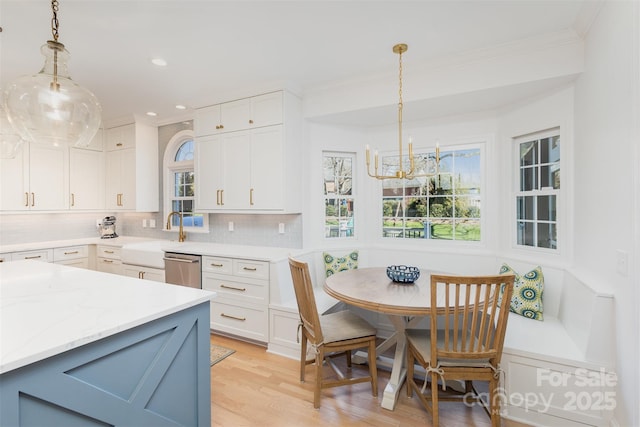 kitchen with sink, tasteful backsplash, decorative light fixtures, breakfast area, and white cabinetry