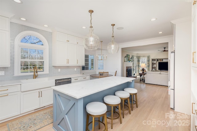 kitchen featuring sink, a center island, decorative light fixtures, white cabinetry, and dishwasher