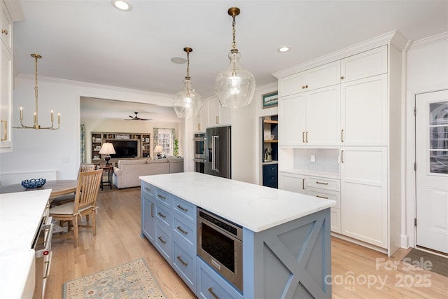 kitchen featuring stainless steel appliances, a center island, ornamental molding, white cabinetry, and pendant lighting