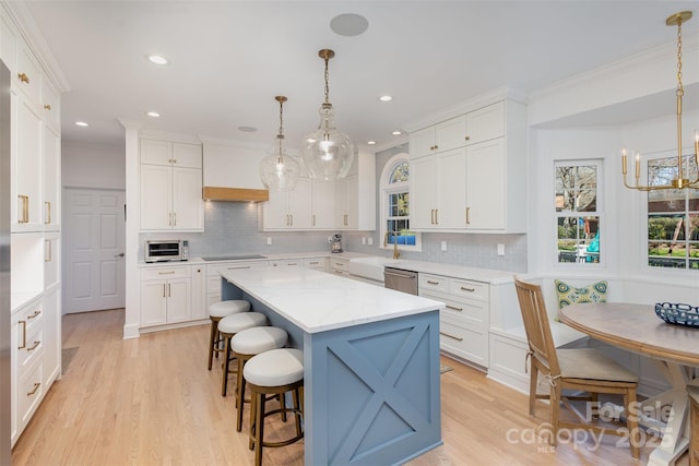 kitchen with a center island, white cabinets, breakfast area, dishwasher, and hanging light fixtures