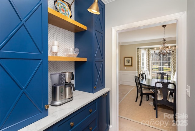 kitchen with light hardwood / wood-style floors, blue cabinets, tasteful backsplash, and light stone countertops