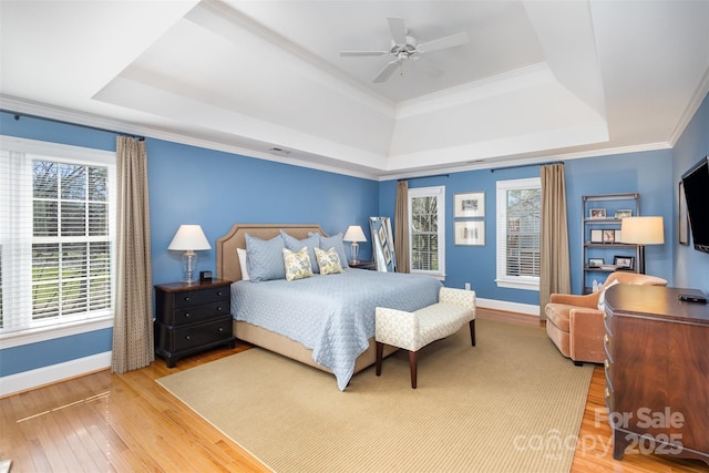 bedroom featuring hardwood / wood-style floors, a raised ceiling, ceiling fan, and ornamental molding