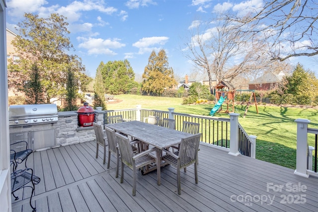 wooden terrace with a playground, grilling area, a yard, and exterior kitchen