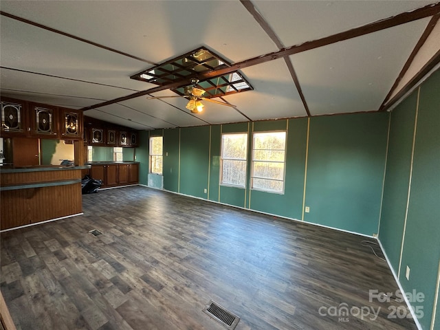 unfurnished living room featuring lofted ceiling, dark wood-style floors, a ceiling fan, and visible vents