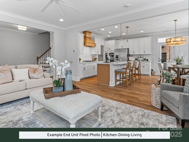 living room with stairway, recessed lighting, ceiling fan, ornamental molding, and light wood-style floors