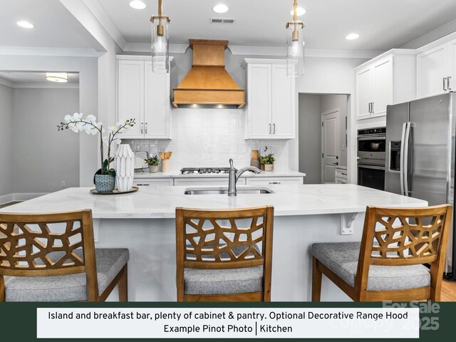 kitchen with visible vents, crown molding, appliances with stainless steel finishes, custom exhaust hood, and a sink