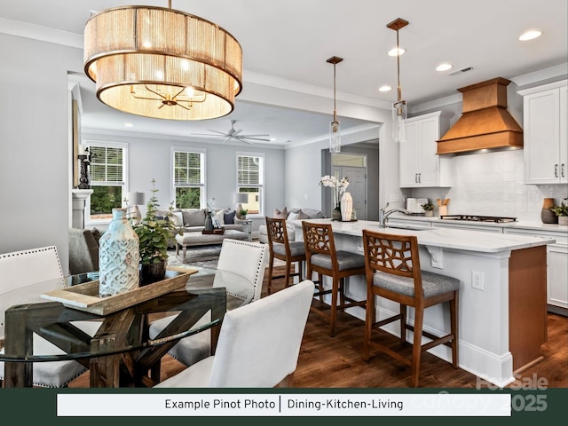 dining space with visible vents, ornamental molding, ceiling fan with notable chandelier, recessed lighting, and dark wood-style floors