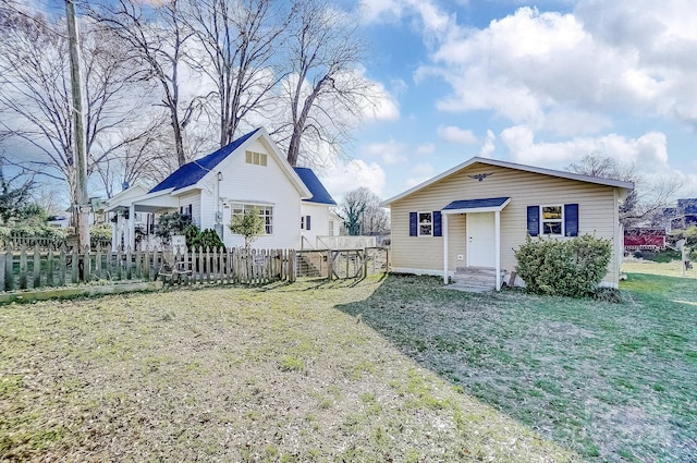 bungalow-style home featuring entry steps, fence, and a front lawn