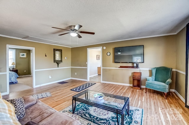 living area with ornamental molding, a ceiling fan, a textured ceiling, and wood finished floors