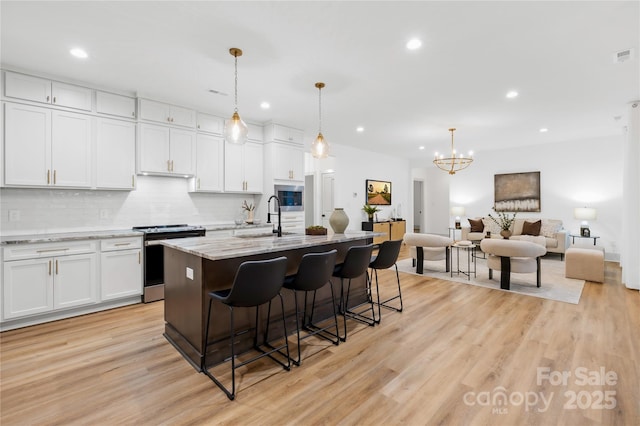 5147 Star Magnolia Ct, Clover, SC 29710 - kitchen with white cabinets, light wood-style flooring, stainless steel range with electric cooktop, tasteful backsplash, and a breakfast bar area