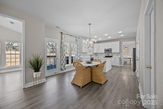 dining space featuring a notable chandelier, sink, and wood-type flooring