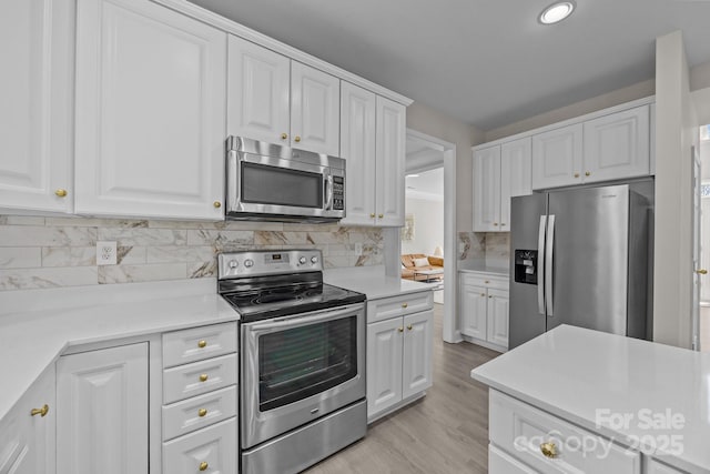 kitchen featuring light hardwood / wood-style floors, stainless steel appliances, white cabinetry, and backsplash