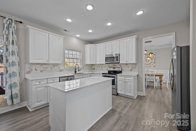 kitchen featuring sink, a center island, white cabinetry, decorative light fixtures, and stainless steel appliances