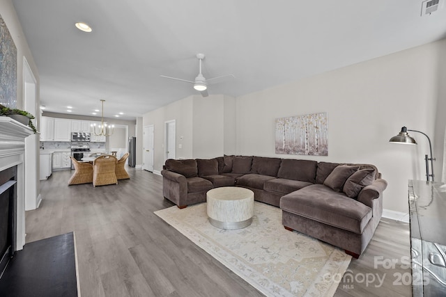 living room with ceiling fan with notable chandelier and wood-type flooring