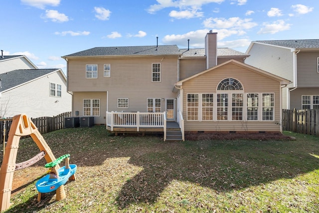 rear view of property featuring central air condition unit, a lawn, and a wooden deck