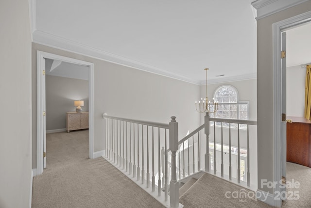 corridor with an inviting chandelier, crown molding, and light colored carpet