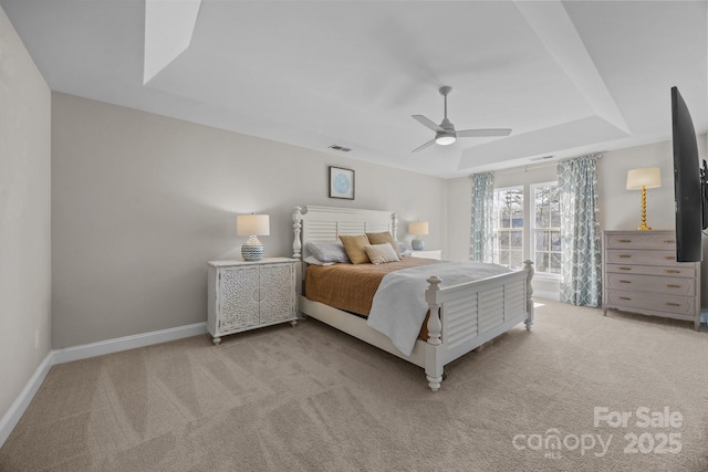 carpeted bedroom featuring a tray ceiling and ceiling fan