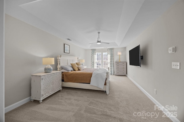 bedroom featuring ceiling fan, a tray ceiling, and light colored carpet