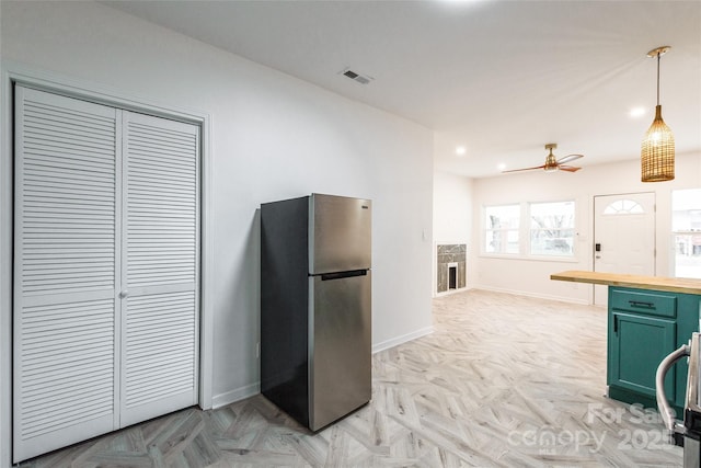 kitchen with decorative light fixtures, visible vents, green cabinets, freestanding refrigerator, and butcher block countertops