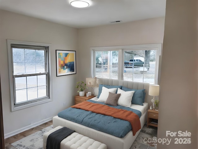 bedroom with visible vents, baseboards, and wood finished floors