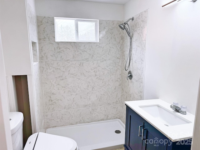 bathroom featuring toilet, a tile shower, and vanity