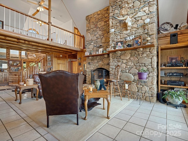 tiled living area featuring a stone fireplace, a ceiling fan, a high ceiling, and stairway