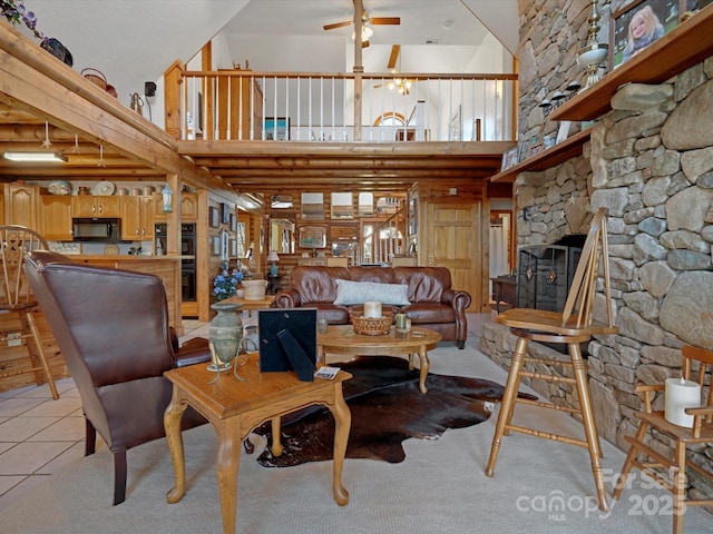 living room featuring ceiling fan, a towering ceiling, light tile patterned floors, and a fireplace