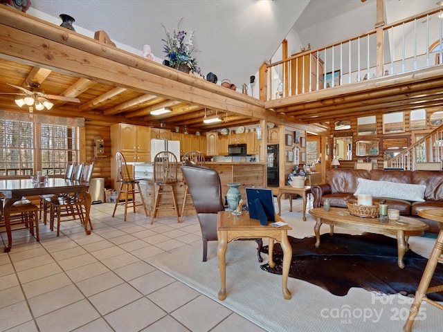 living area with a wealth of natural light, light tile patterned floors, beam ceiling, and ceiling fan