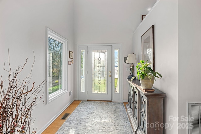 foyer entrance featuring light wood-style flooring, visible vents, and baseboards