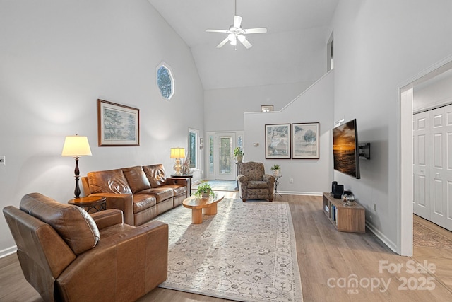 living area with light wood finished floors, baseboards, high vaulted ceiling, and ceiling fan