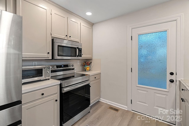 kitchen featuring a toaster, visible vents, white cabinets, appliances with stainless steel finishes, and light countertops