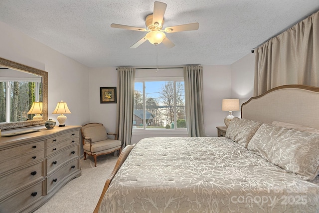 bedroom with a ceiling fan, light colored carpet, and a textured ceiling