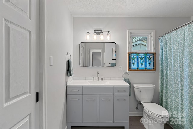 full bathroom with baseboards, a textured ceiling, toilet, and vanity