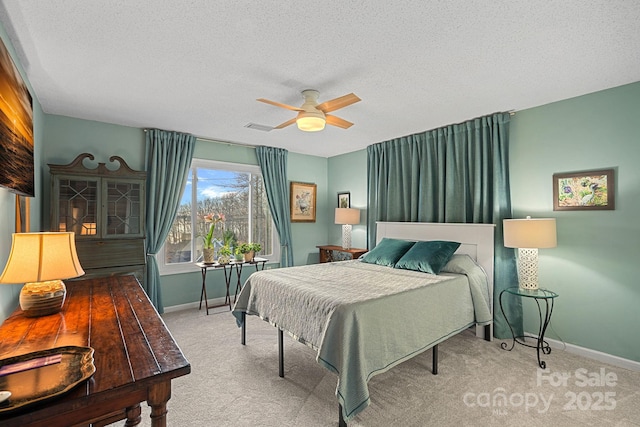 bedroom with visible vents, a ceiling fan, light carpet, a textured ceiling, and baseboards