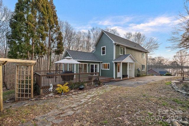 rear view of house featuring a shingled roof and a deck