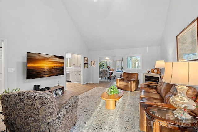 living area with baseboards, light wood-style flooring, and high vaulted ceiling