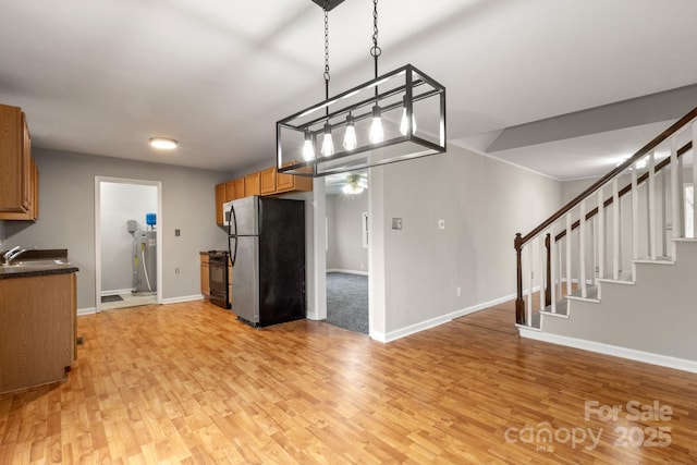 kitchen featuring hanging light fixtures, stainless steel fridge, black range, and light hardwood / wood-style flooring