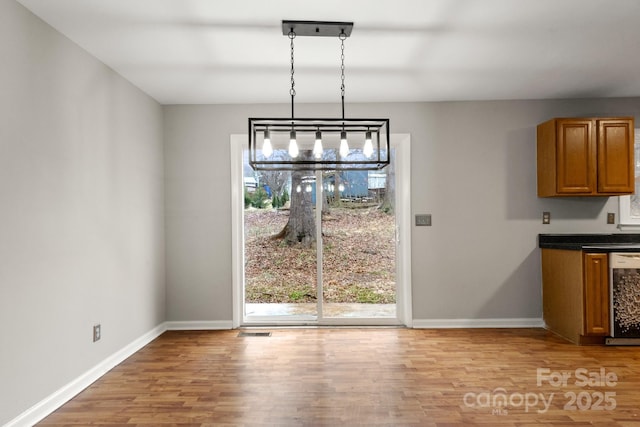 unfurnished dining area with light hardwood / wood-style floors and beverage cooler