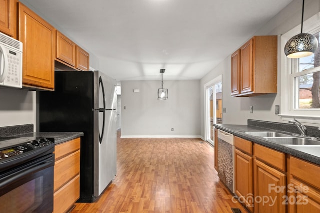 kitchen featuring light wood-type flooring, black electric range oven, sink, dishwasher, and pendant lighting