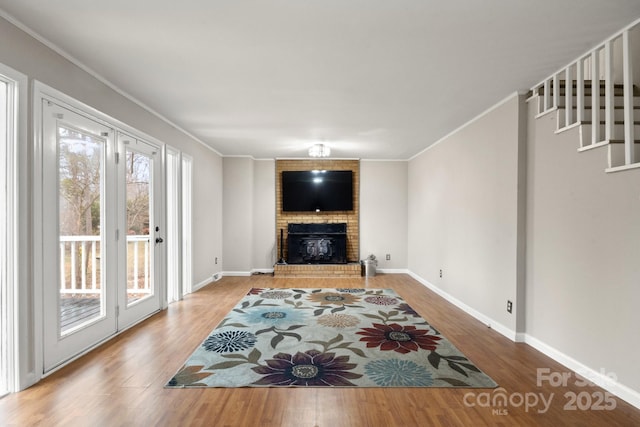 living room with a brick fireplace, crown molding, and wood-type flooring