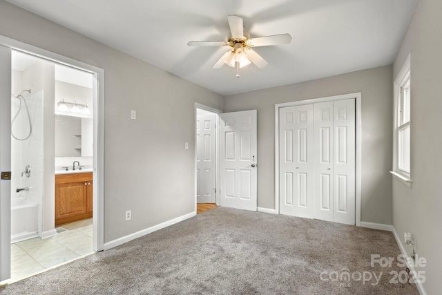 unfurnished bedroom with a closet, sink, ceiling fan, connected bathroom, and light carpet